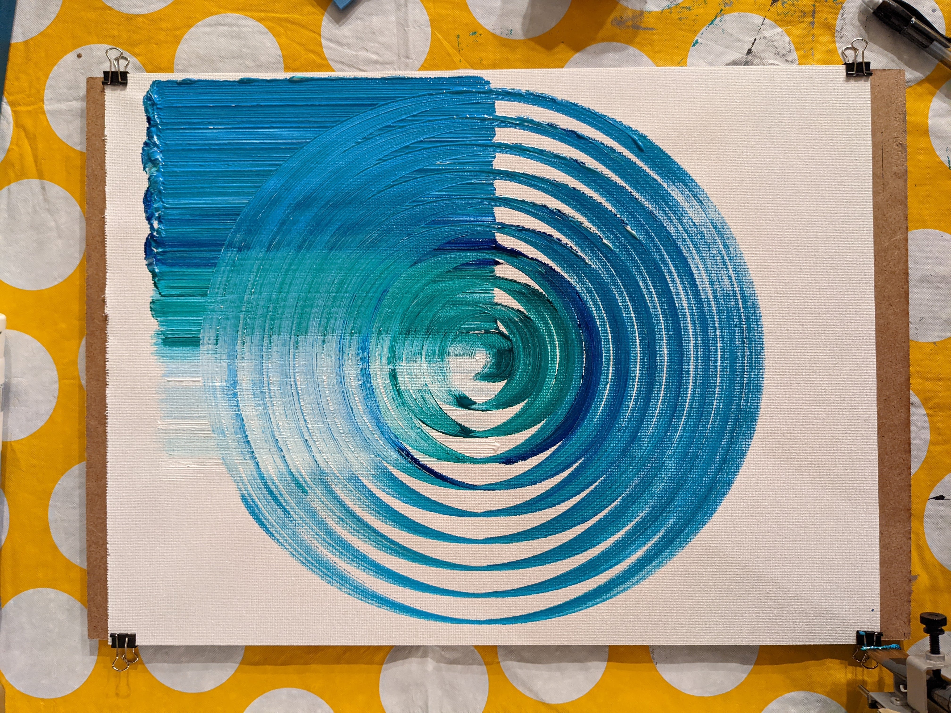 An image of a canvas with perfectly concentric circles and lines painted on it in blue and green.